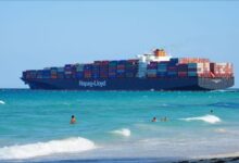 A Hapag-Lloyd container ship full of cargo containers sails on the ocean.